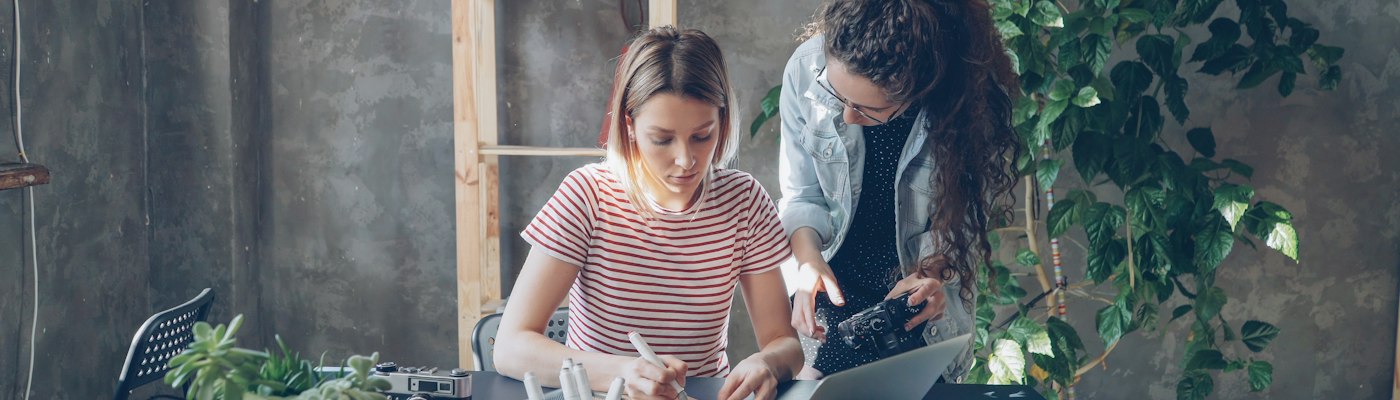 Dos compañeras revisando un trabajo en la mesa de la oficina